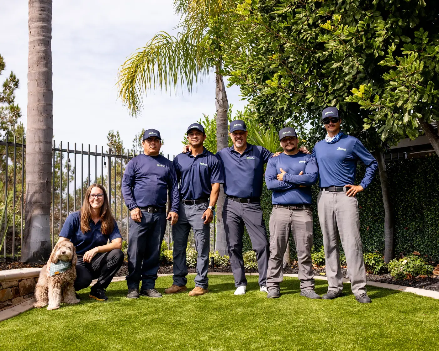 The TurFresh team of artificial turf care experts standing together on a clean turf lawn