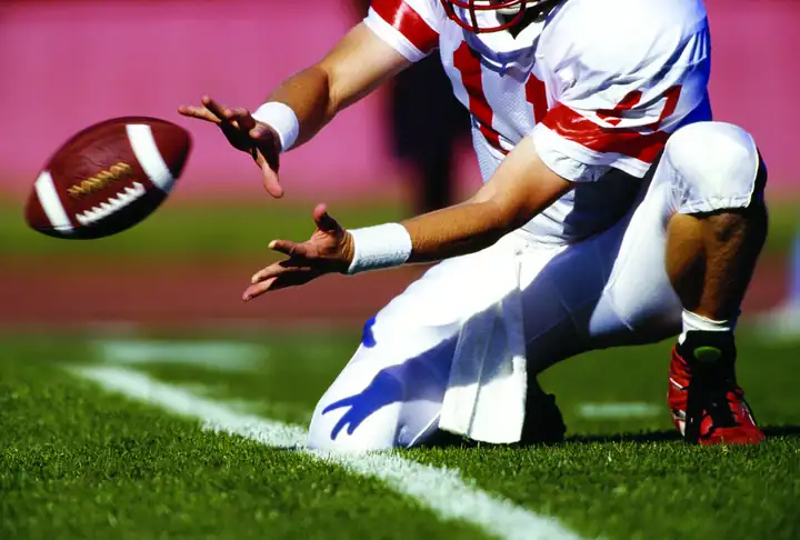 Football player long snapping on game-day artificial turf field cleaned by TurfAid commercial service