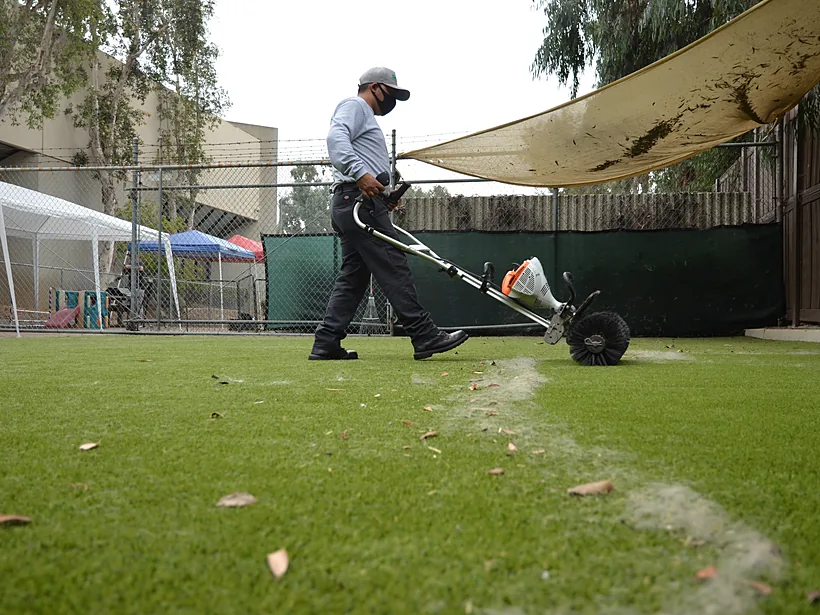 TurFresh technician reblooming artificial turf with a commercial power brush