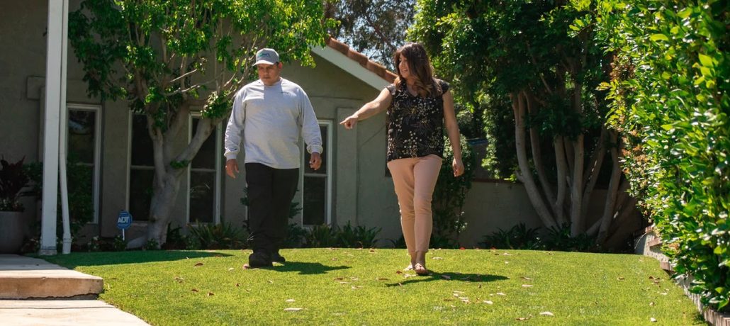 TurFresh professional inspecting and maintaining residential artificial turf lawn.