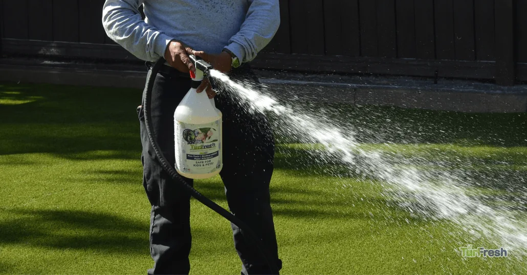 Close-up of a professional applying TurFresh turf deodorizer, a non-toxic, biodegradable formula that safely eliminates odors and refreshes artificial grass for kids and pets.