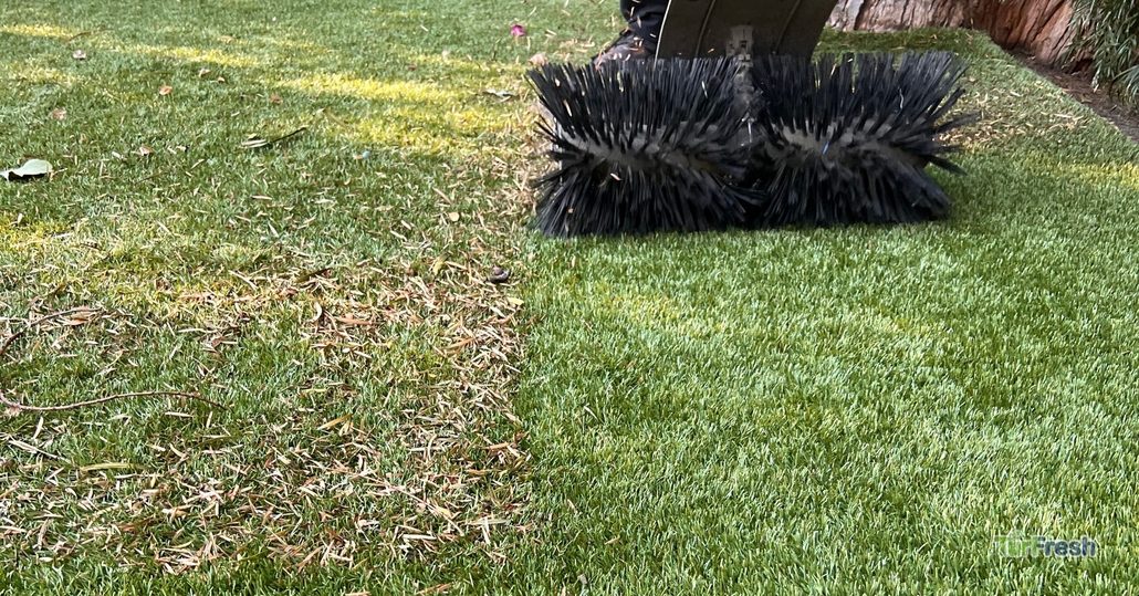 Technician performing TurfBloom fiber restoration service on compacted artificial grass.