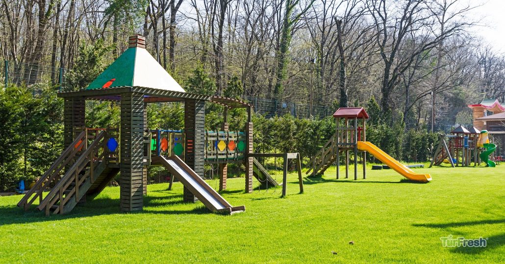 Clean artificial turf playground with wooden play structures after TurFresh professional playground turf maintenance.