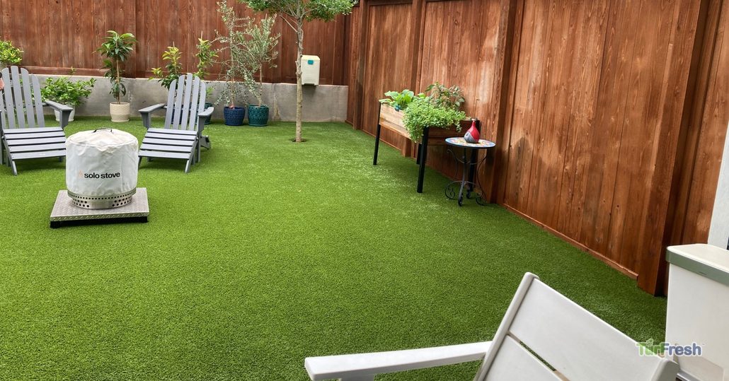 Clean backyard with artificial turf, patio furniture, and garden planters, professionally maintained by TurFresh.