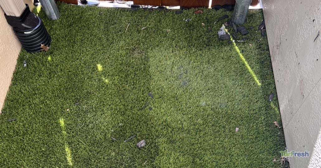 Artificial turf in a tight corner area with debris buildup, TurFresh cleaning and maintenance zone.