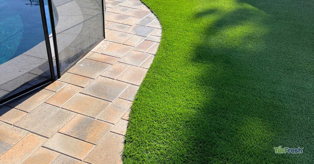 Clean artificial turf beside a pool deck before a home listing maintained by TurFresh