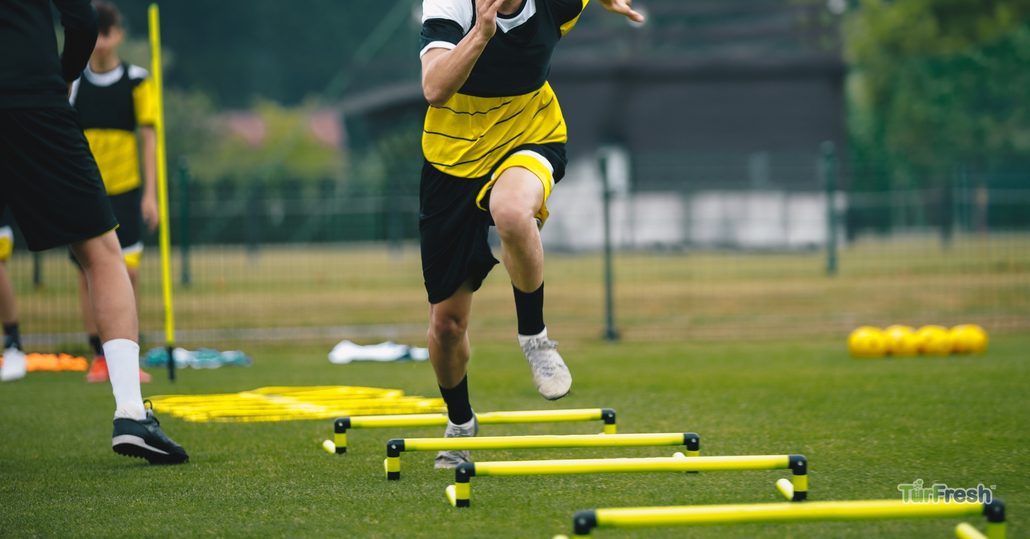 Athletes training on clean artificial turf sports field maintained by TurFresh professional turf cleaning service.